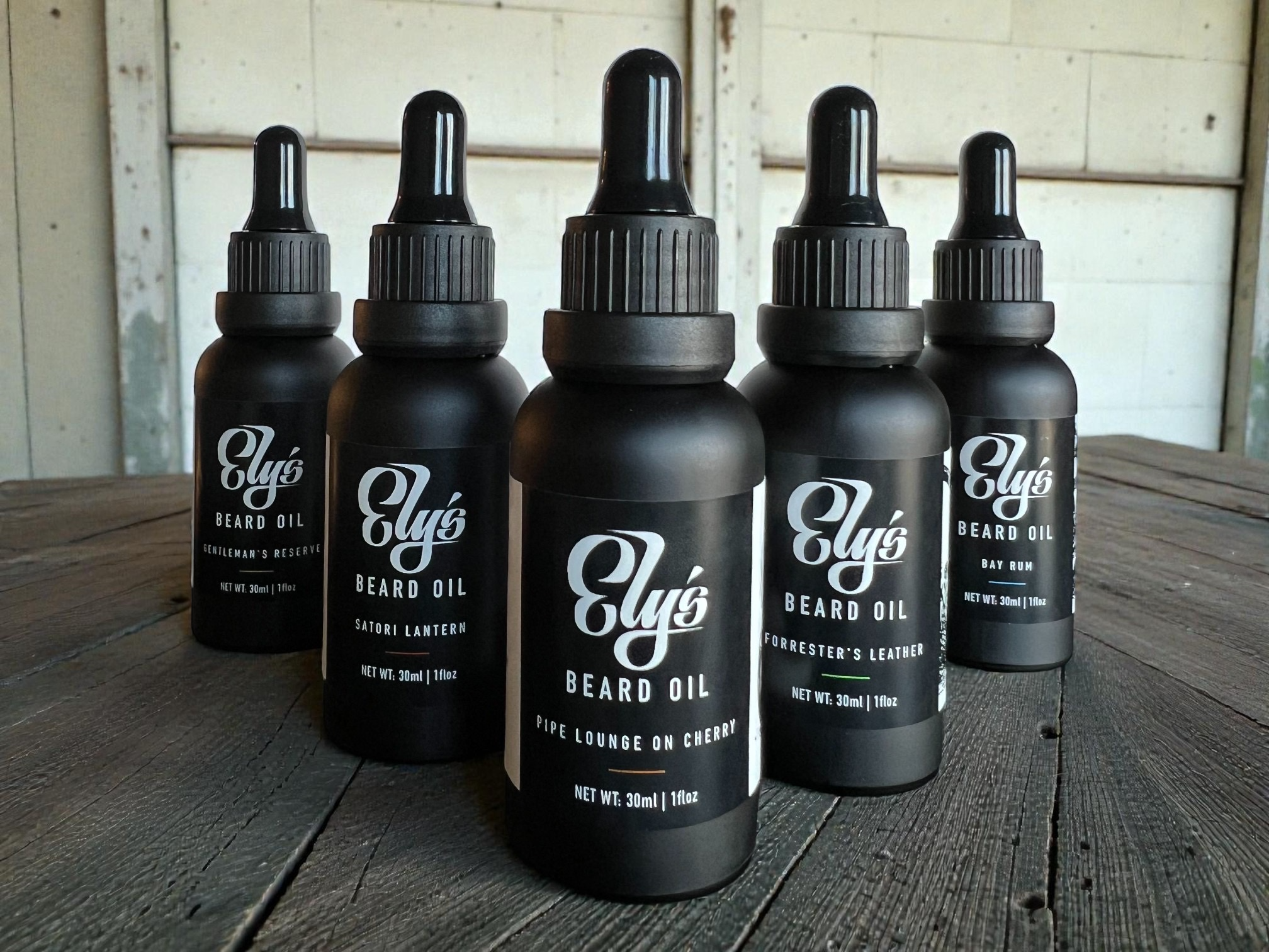 A row of Ely's Beard Oil bottles on a wooden table.